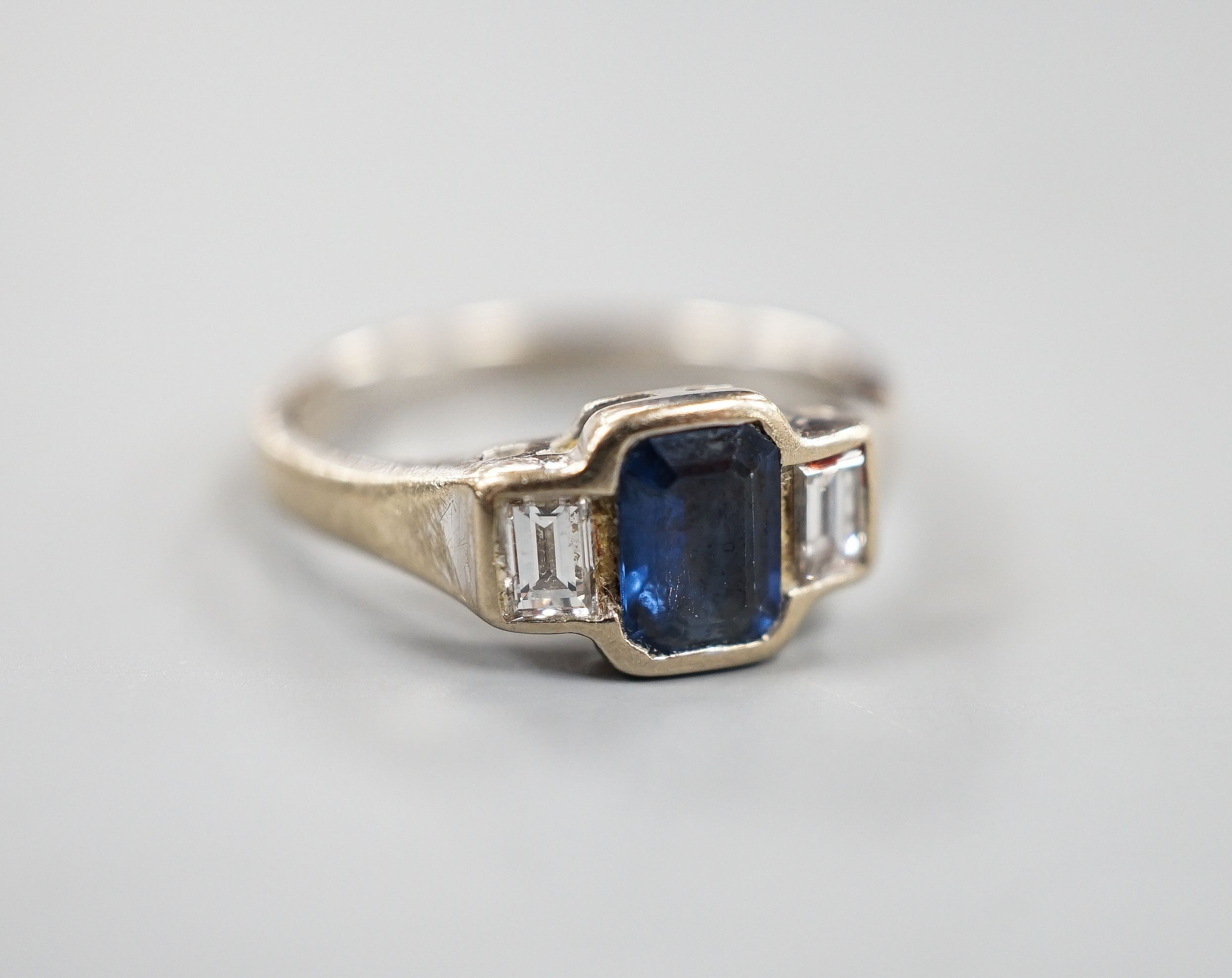 A modern 18ct white gold, collet set sapphire and diamond three stone ring, size L, gross weight 3.8 grams.